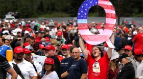 David Reinert holds up a large "Q" sign that represents QAnon while waiting in line to see then-President Donald Trump at his rally in Wilkes Barre, Pa., on Aug. 2, 2018.