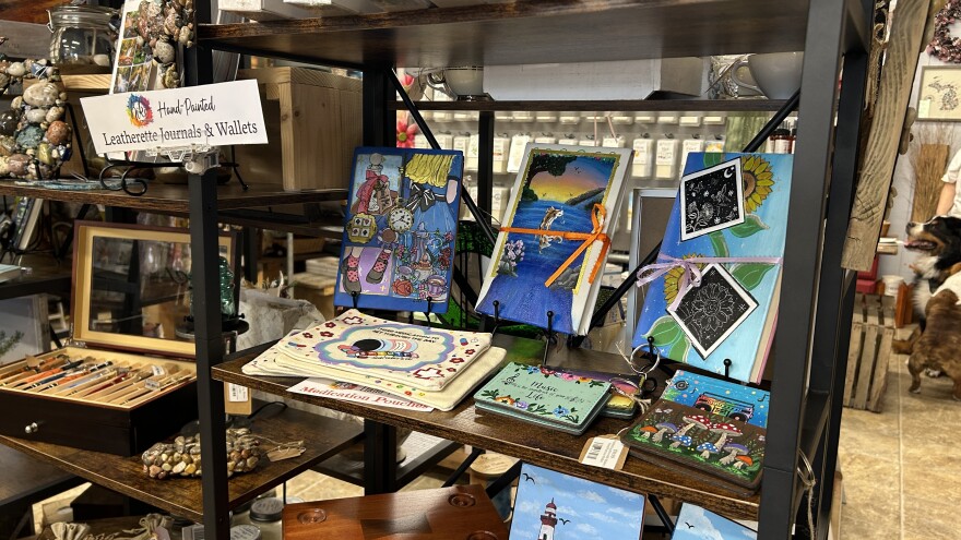 A store display featuring hand-painted journals and pouches.