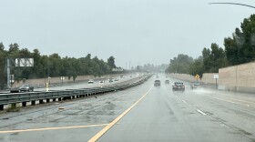 A view looking out of a vehicle windshield at a freeway during a rainstorm. 