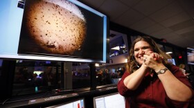 An engineer smiles next to an image of Mars sent from the InSight lander shortly after it landed on Mars in the mission support area of the space flight operation facility at NASA's Jet Propulsion Laboratory Monday, Nov. 26, 2018, in Pasadena, Calif. (Al Seib/Los Angeles Times via AP, Pool)