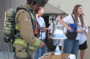 A man in a firefighter uniform rings a silver bell. 