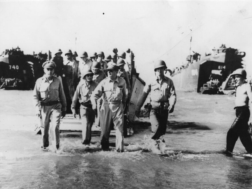 General Douglas MacArthur goes ashore from a landing craft with a party of the invading force at Luzon. This photo, taken in 1945, shows MacArthur reenacting a a similar scene from 1944.