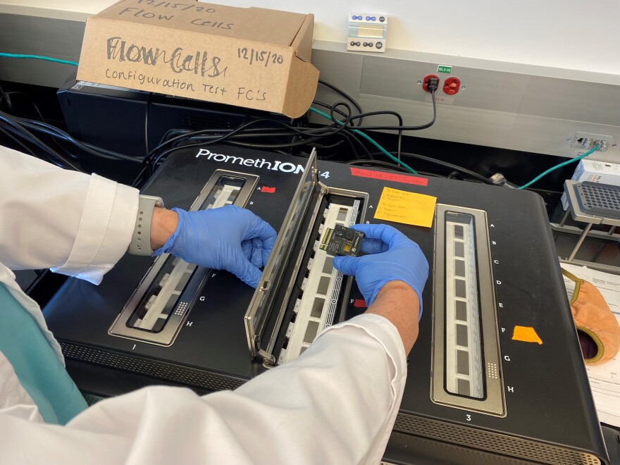 Jessica Schlueter loads a sequencing chip with 96 coronavirus test samples onto the sequencer, which researchers have nicknamed "Big Bird."