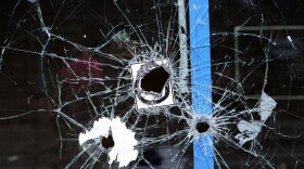 Bullet holes from a prior shooting are still visible in a storefront window at the scene of a fatal overnight shooting on South Street in Philadelphia on June 5, 2022.