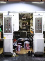 Workers in green polo shirts and blue caps monitor machines making plastic products at the Dongguan Fangjie Printing and Packaging Company.