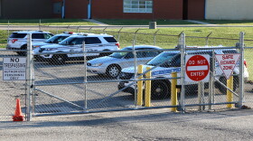 Dayton Police cars behind a fence. Signs warn people not to trespass and not to enter. Another sign declares the area a safe exchange zone.
