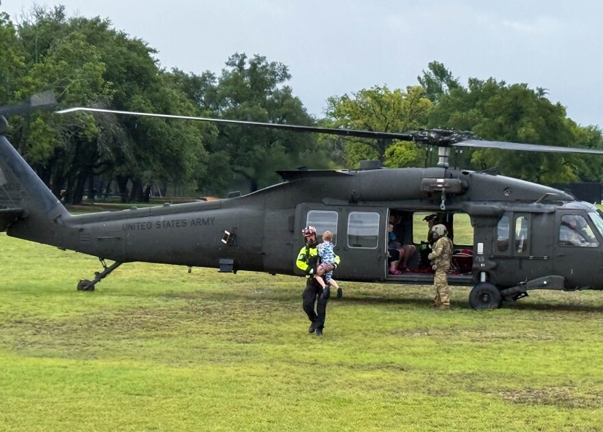 A person carries a child away from a helicopter following evacuations at Hope House on Saturday July 5, 2025. Photo courtesy David Gould