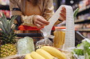 A person reads a receipt held over a cart of groceries.