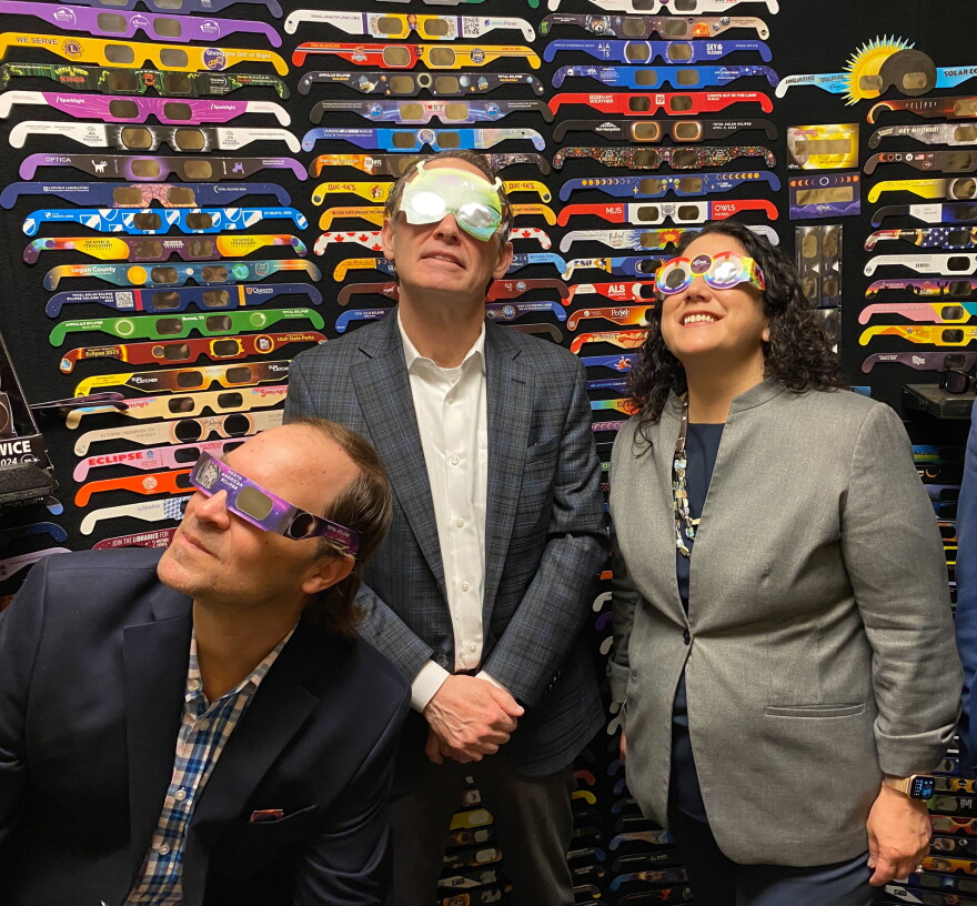 Jerit (center) tries on a pair of solar glasses alongside the head of the federal Small Business Administration, Isabella Casillas Guzman (right) and Jason Lewin with American Paper Optics.