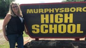 Teacher in front of high school sign