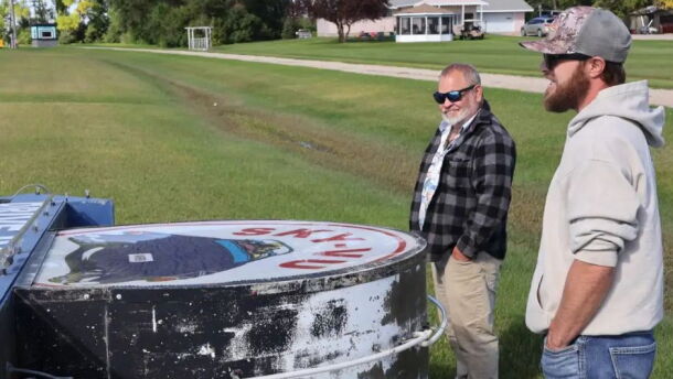 Steve Novak, left, and Chris Novak, right, look at the downed marquee of Sky-Vu in Warren, Minn., on Sunday. The wind's strength was so great that it bent over the metal poles that held up the sign. | MPR News