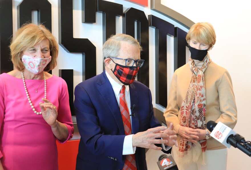 Gov. Mike DeWine speaks with reporters alongside First Lady Fran DeWine (left) and OSU President Kristina Johnson