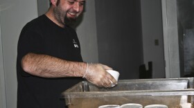 Adam Wiemold, volunteer, smiles as he prepares cups of cereal for care packages at the Larimer County Food Bank.