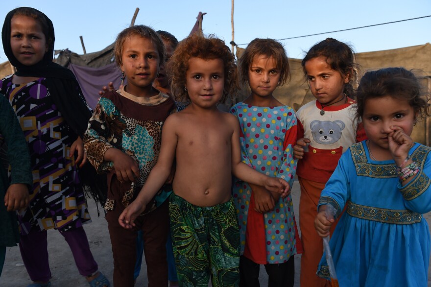 Afghan children look on at a refugee camp in Jalalabad on May 3, 2015. Like thousands of Afghan returnees, Neik Mohammad became unwanted in Pakistan after a Taliban massacre at a Peshawar school, forcing him to return home to a life of misery and fear in a squalid refugee settlement.