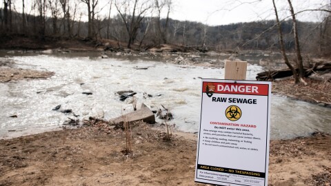 A warning sign is seen at the sight of a massive pipe rupture, as sewage flows into the Potomac River, right, in Glen Echo, Md., Jan. 23, 2026.
