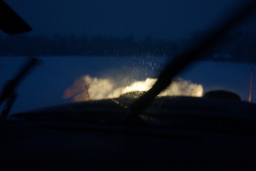  View from plow truck at night. Dark field and bright lights