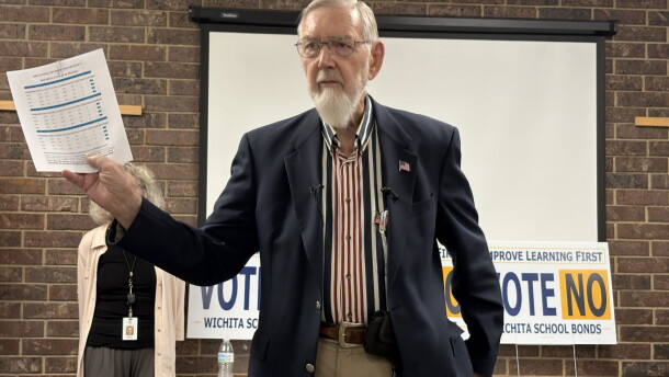 Walt Chappell, a former Kansas school board member and treasurer for the campaign opposing the bond issue, holds up a piece of paper with measures of student proficiency. He argues spending money on new facilities will not improve student outcomes.