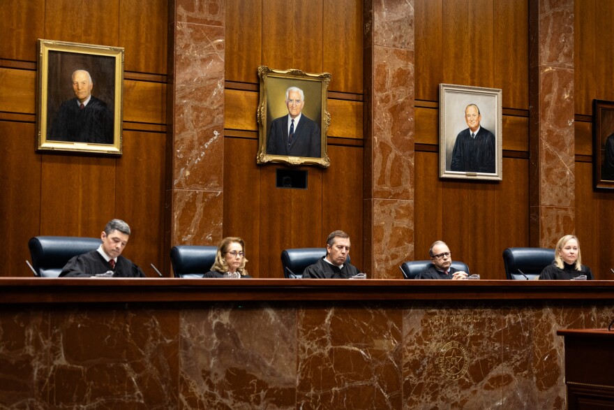Texas Supreme Court justices sit pensively at the dias