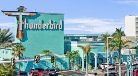 Exterior of a green building that says Thunderbird, with the T in the shape of a bird