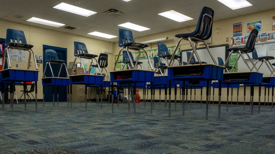 Chairs sit stacked on desks in an empty classroom