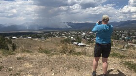 Woman takes a photo of smoke in the distance.