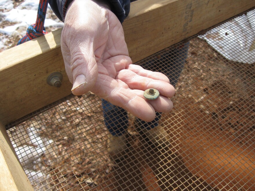 DePratter displays a button from a Union officer's uniform found at Camp Asylum.
