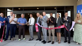 A line of officials from UMC and the county smile as they cut a ribbon in front of the center