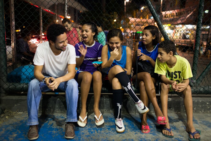 Guilherme Silva (left) is a volunteer coach with Estrela Sports, which trains both boys and girls to play soccer. He's sitting with (from left) Victoria Silva Rodrigues, 13, Lahis Maria Ramos Veras, 14, and Milena Medeiros dos Santos, 16, and her brother Vinicius Medeiros, 12.