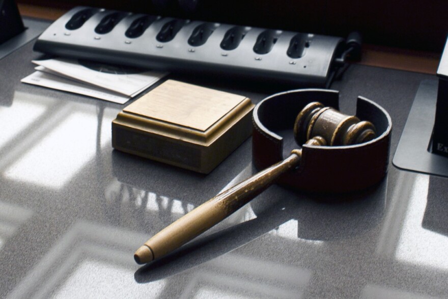On a gray desk, a wooden gavel sits next to a wooden block