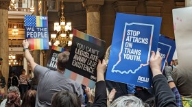 A crowd holds signs at Indiana's 2023 LGBTQ+ Statehouse Day.