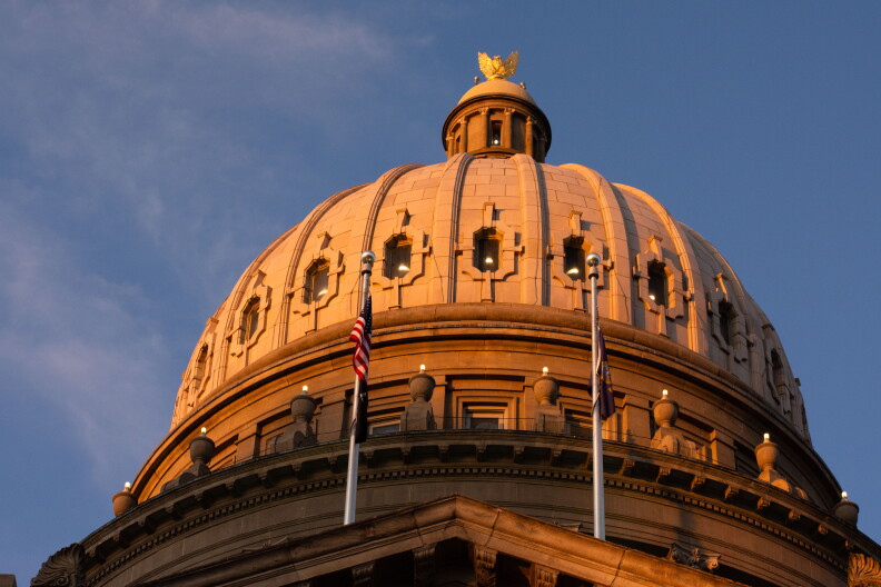 The dome of the Idaho Statehouse at sunset with an American flag and Idaho flag.