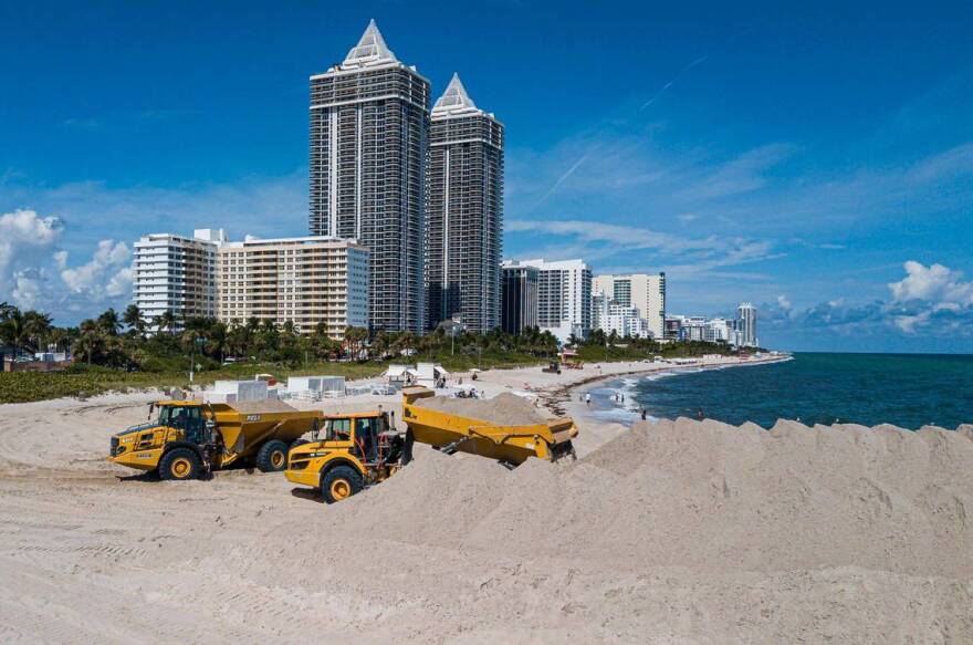 Trucks offload sand near Indian Beach Park in Miami Beach
