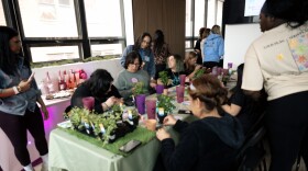 Participants in Respira Counseling and Wellness's self-care retreat on March 7, 2026 paint flower pots, as Respira founder Shasterin Valentin (standing, center) encourages the women to name their new plants after themselves as a reminder to take care of oneself as diligently.