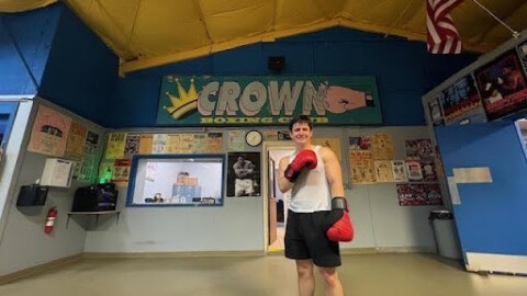 Alex Ziouras poses in front of his team's Crown Boxing Club sign.