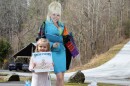 Girl holds a copy of Dolly Parton's book in front of a cardboard cut-out of the country singer.