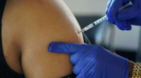 FILE - A Jackson, Miss., resident receives a Pfizer booster shot from a nurse at a vaccination site Feb. 8, 2022. The Biden administration hopes to make getting a COVID-19 booster as routine as going in for the yearly flu shot. (AP Photo/Rogelio V. Solis, File)