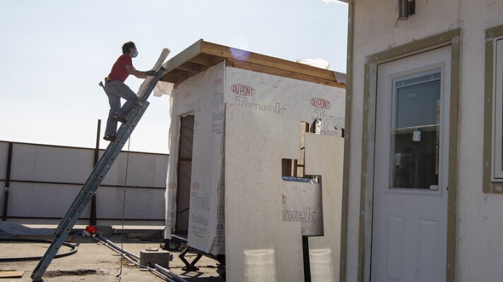 A construction worker scales a ladder up a tiny home