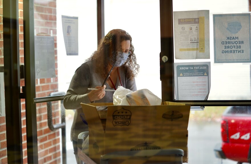 Billie Morton wheels carts of food and supplies through the front doors of The Neighborhood House on Dec. 16, 2020.