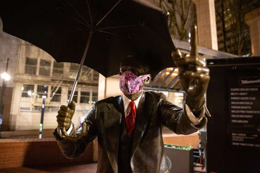 The Umbrella Man statue wears a mask in Pioneer Courthouse Square in Portland, Ore., Saturday, April 18, 2020. Public health officials have encouraged people to wear masks to slow the spread of COVID-19.