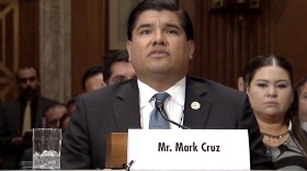 Man at a table with a title card that says Mr. Mark Cruz.