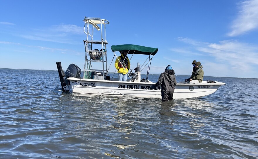 A small rescue boat with people next to it.