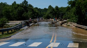 Residents of Saxapahaw, NC walk over the Buddy Collins bridge as the Haw river floods the town after a night of torrential rain on Monday July 7, 2025.