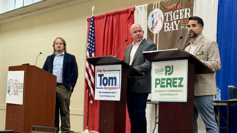 Tallahassee City Commission Seat 3 candidates Tom Derzypolski (center) and PJ Perez (right) participating in a Capitol City Tiger Bay debate moderated by WFSU Public Media reporter Tristan Wood (left) on Sept. 29, 2026.