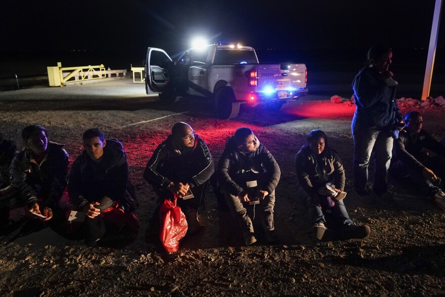 FILE - Migrants wait to be processed after crossing the border on Jan. 6, 2023, near Yuma, Ariz.