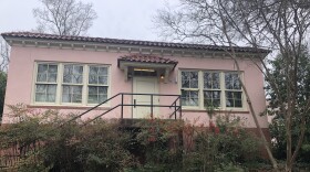 A small pink stucco building with cream trim and a red tile roof.