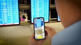 A person using an app on their phone to help read a screen at the airport 