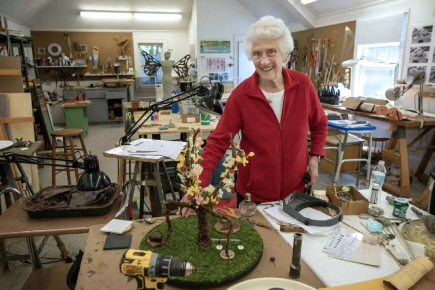 Nancy Schön with a recent sculpture that shows the branches of government, once blossoming, now broken.