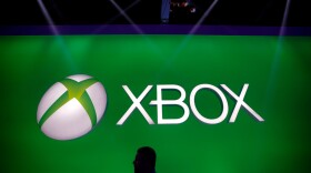 A man walks past the Xbox logo at the Microsoft booth during the E3 game show in Los Angeles, Tuesday, June 11, 2013.
