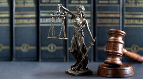 A justice statue rests on a desk next to a judge's gavel.