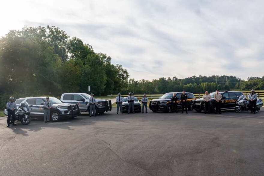 South Carolina police officers stand in front of patrol cars.